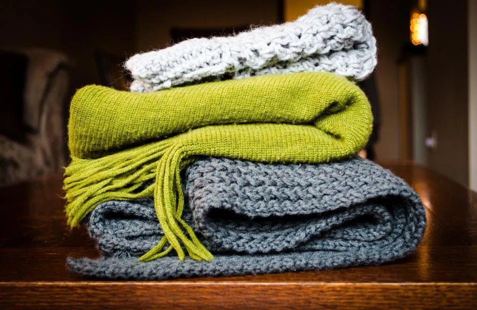 Stack of folded knit blankets and scarves